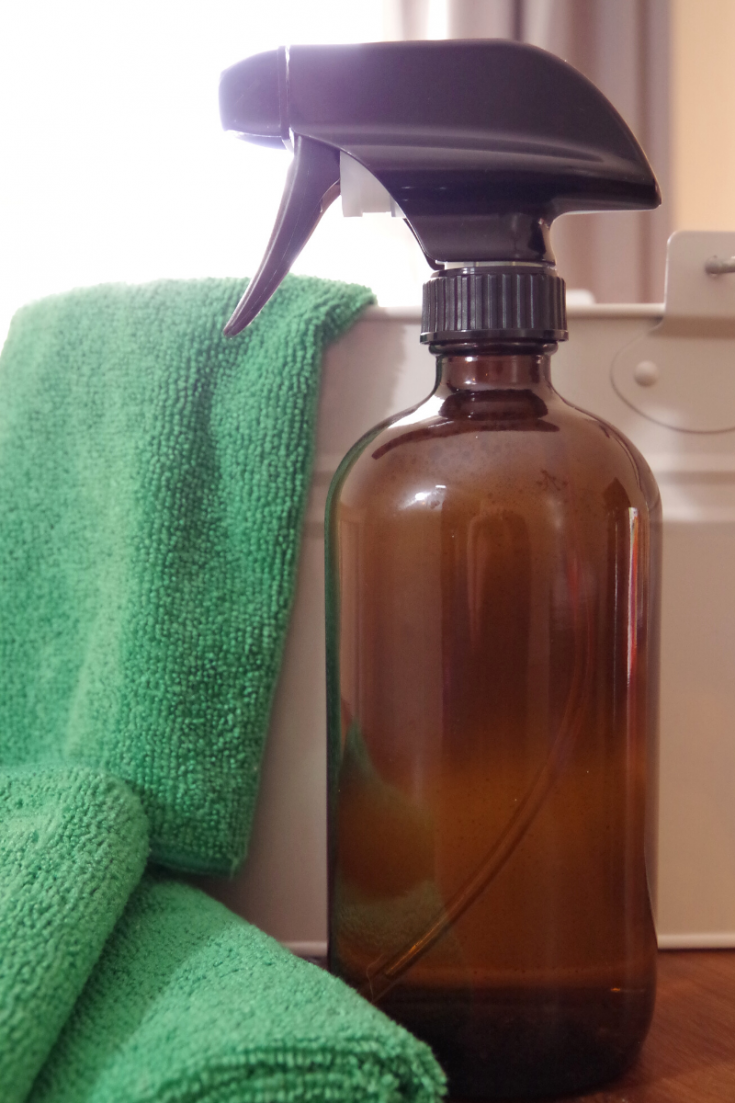 Homemade all-purpose cleaner in an amber glass spray bottle with microfiber cloth.